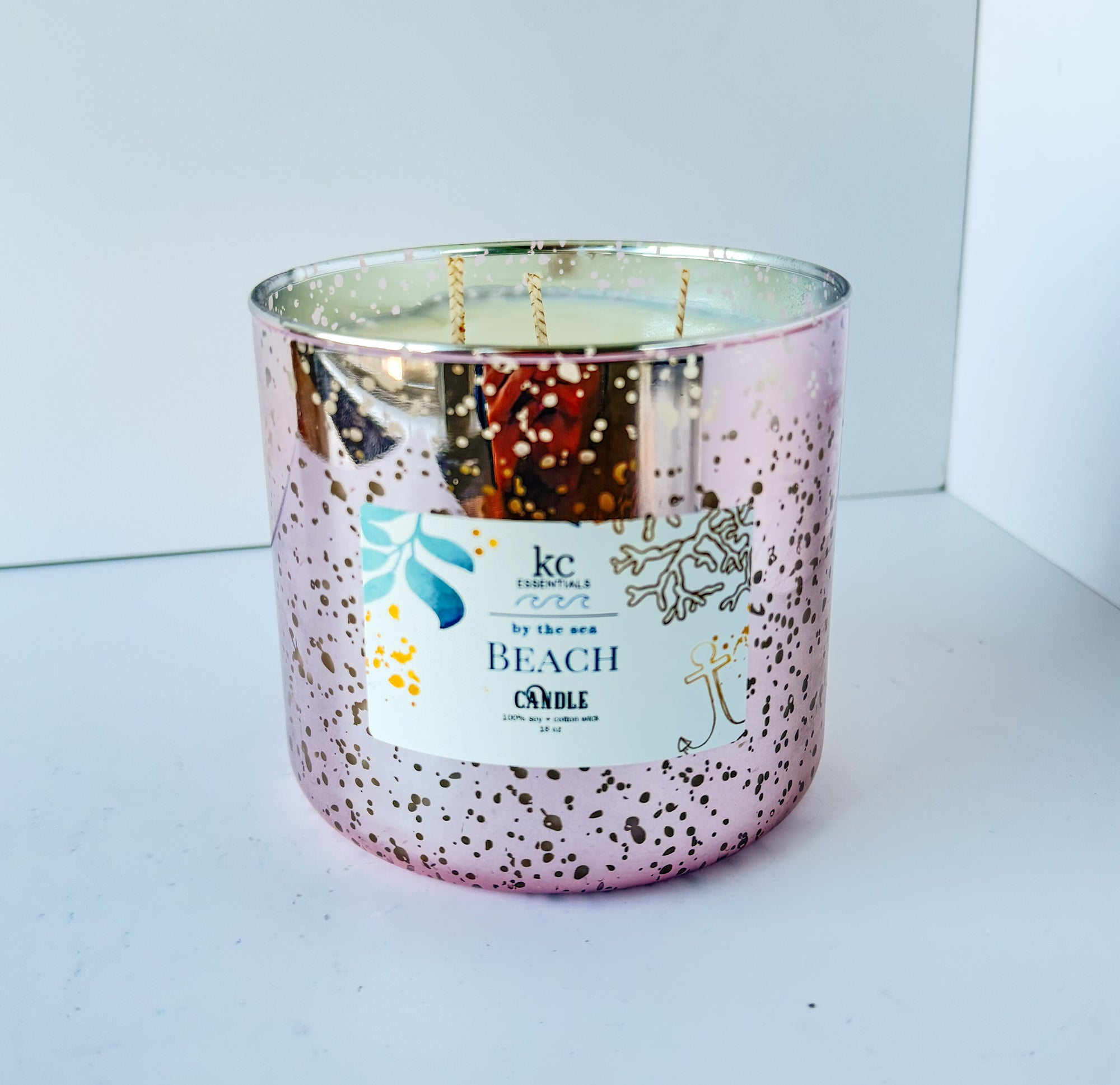 Speckled pink candle labeled 'Beach' on a white surface, beach scented, 3 cotton wicks, 100% soy candle