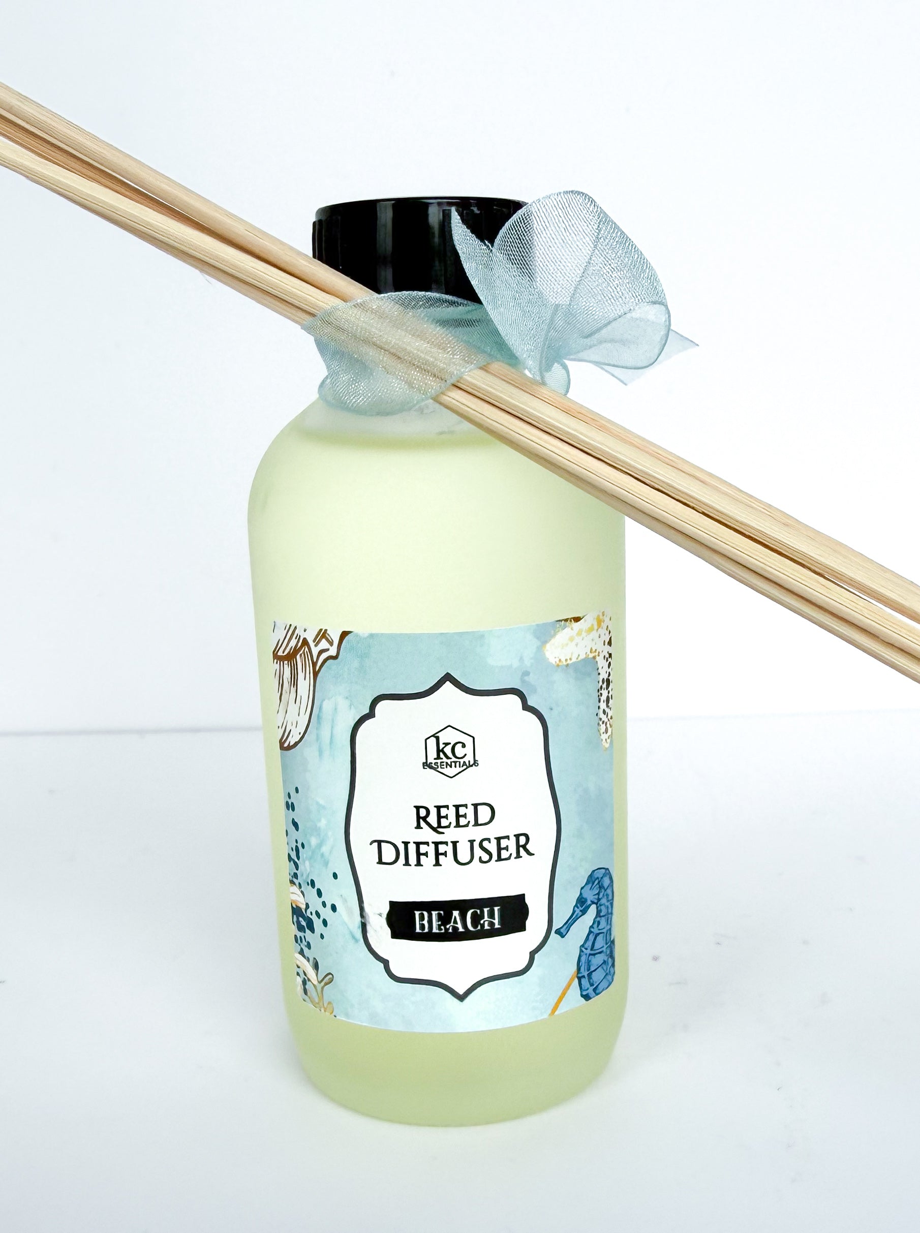 Reed diffuser with 'Beach' label and wooden sticks on a white background, all natural ingredients, beach scented
