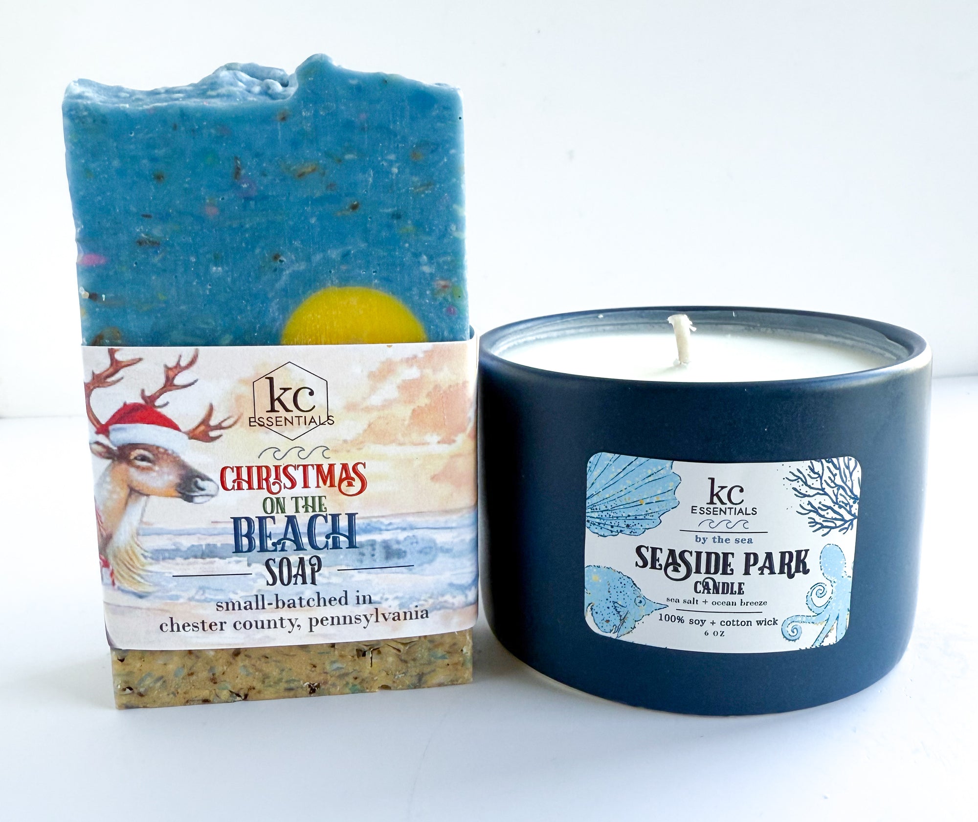 Soap bar and candle with 'Christmas on the Beach' branding on a white background. Navy ceramic candle vessel, seaside park beach, candle, 100% soy candle, sea salt and ocean breeze scented